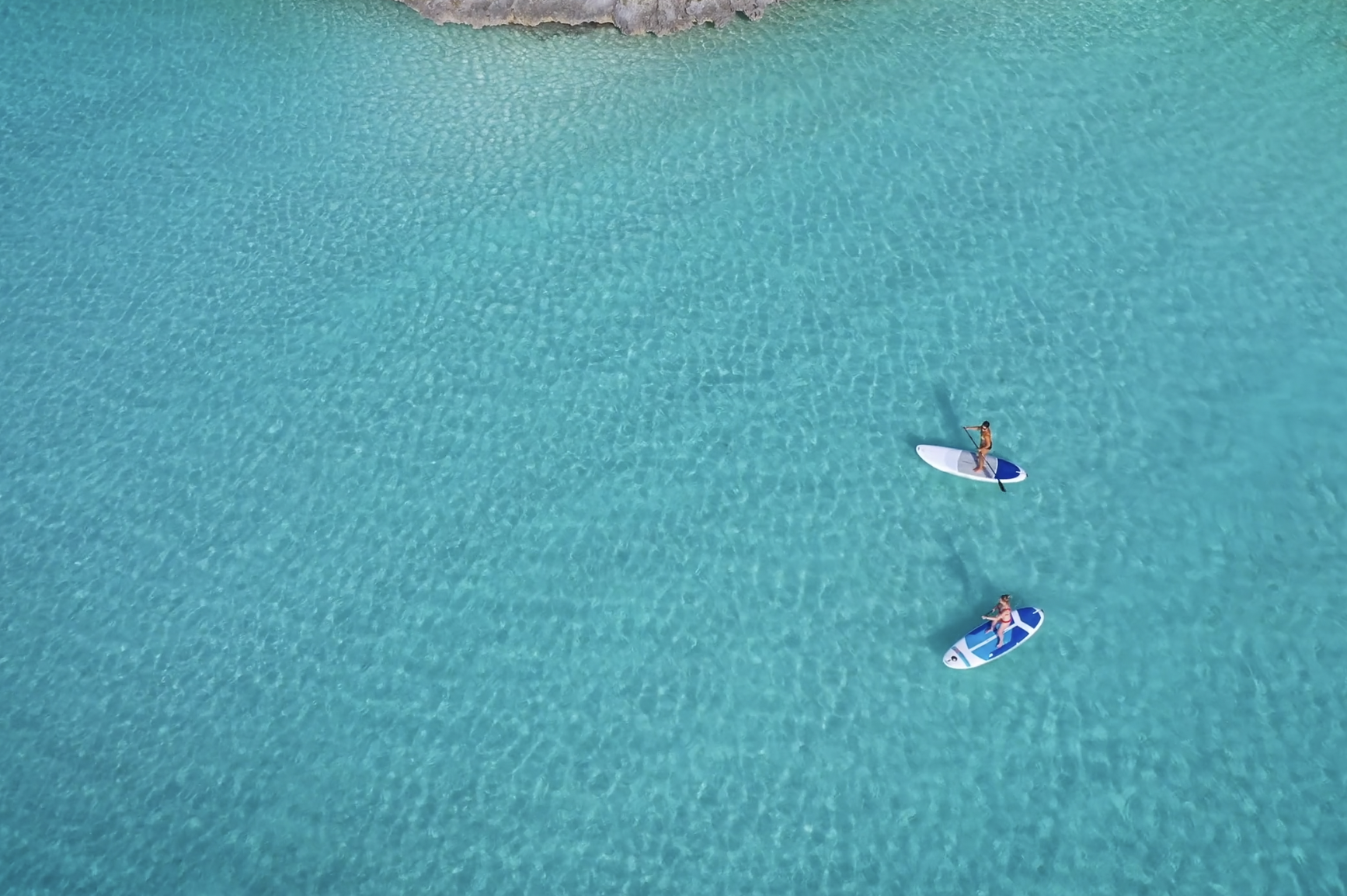 Two people paddleboarding near The Abaco Club