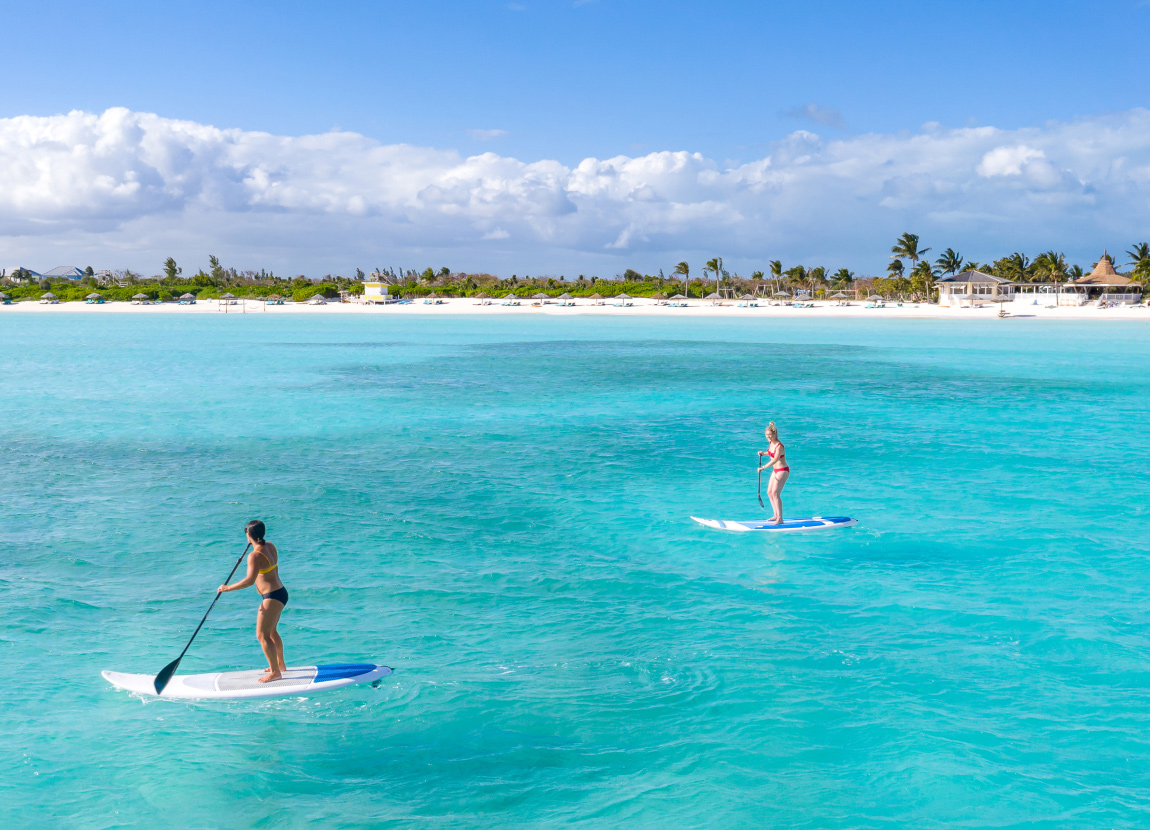 Two people paddle boarding near The Abaco Club